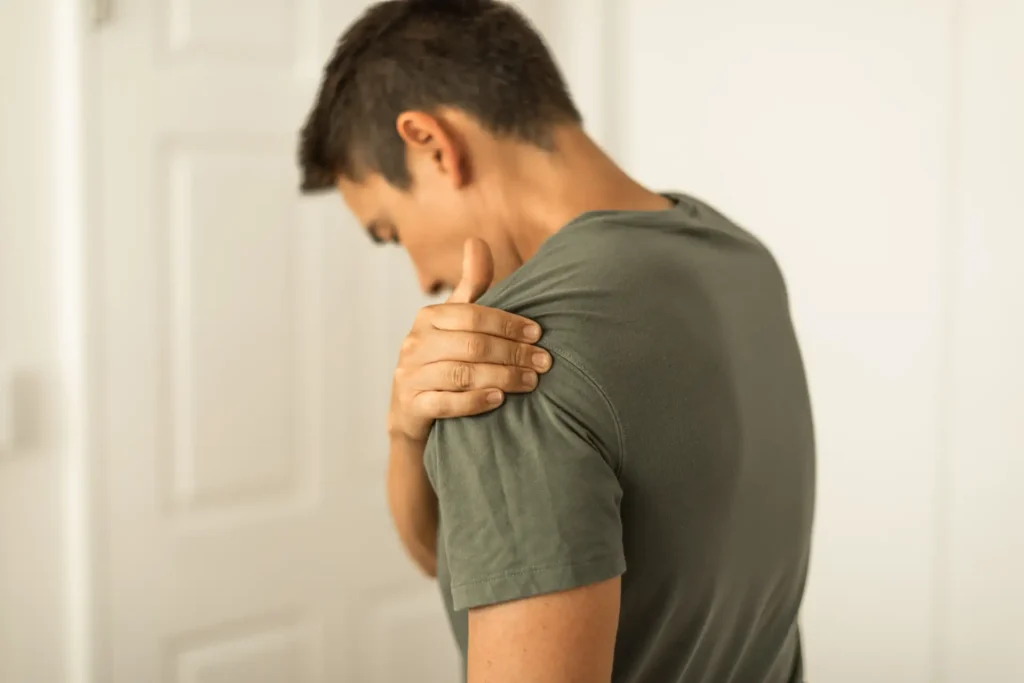 Young man gripping his sore shoulder